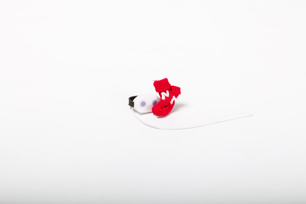 Dos pequeñas medias rojas bordadas con la `N` blanca de Netflix y un casco blanco de realidad virtual en miniatura