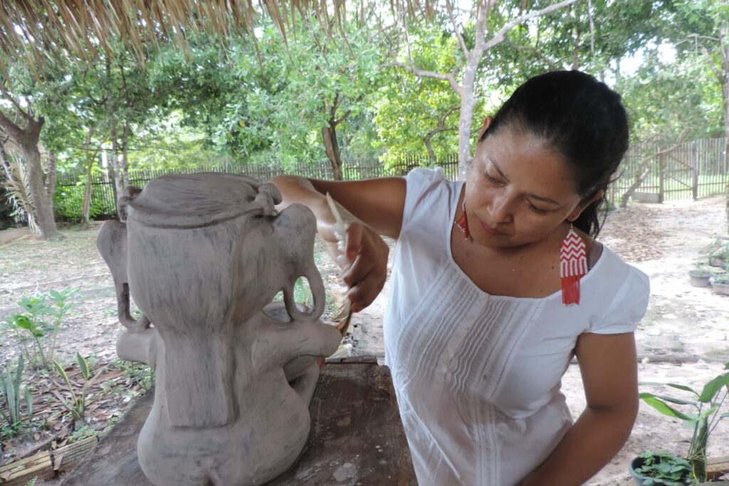 Una mujer indígena trabajando en una pieza de cerámica