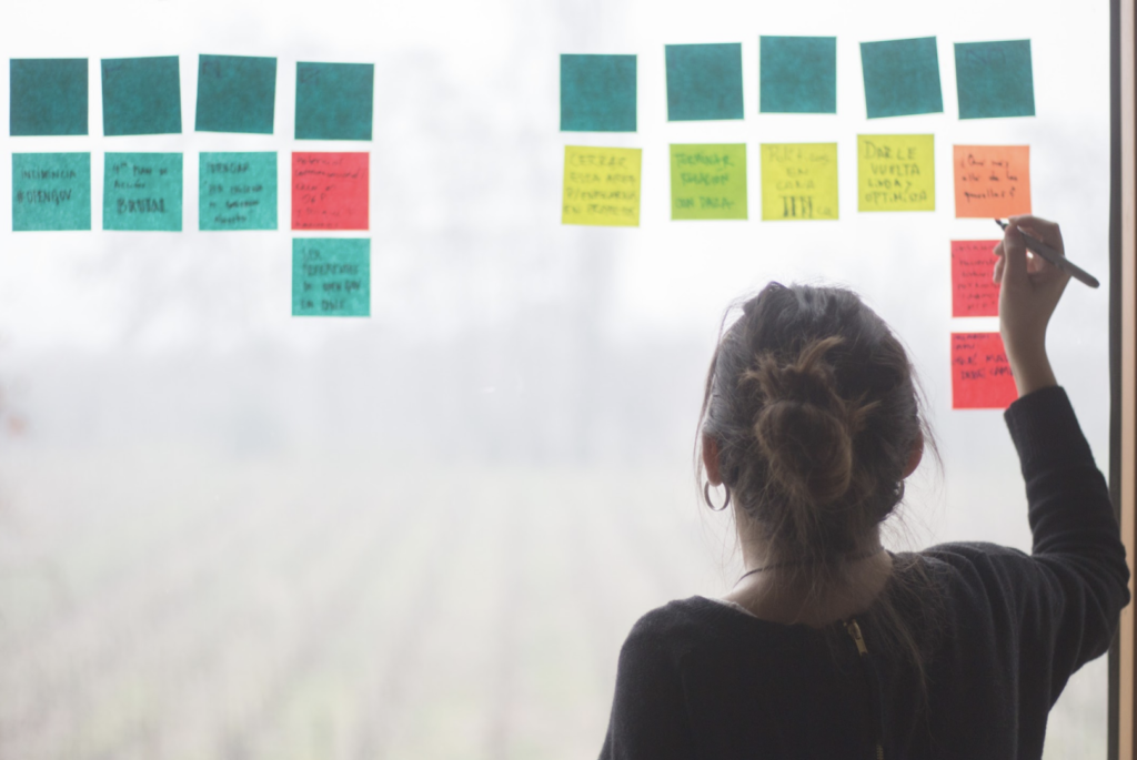 A woman writes notes on a window. 
