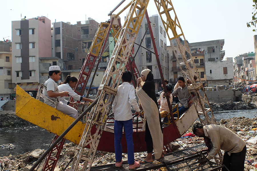 Children play happily on a swing made of waste materials